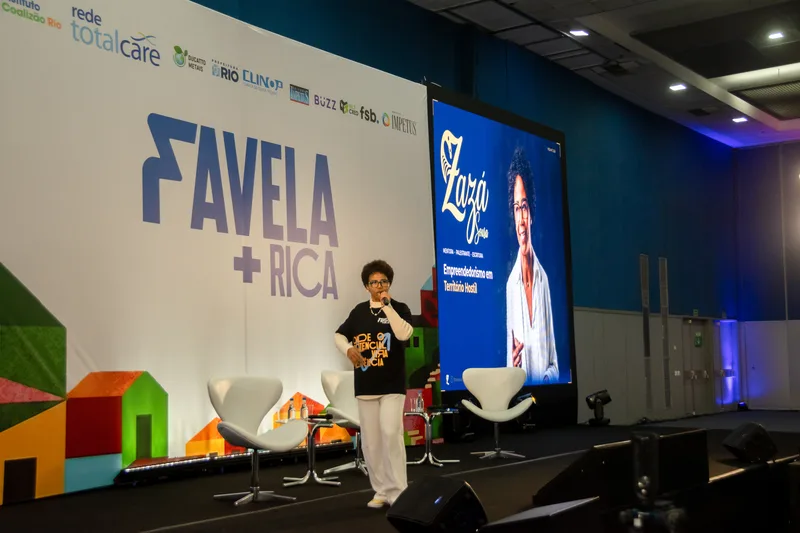 Zazá Sousa no palco do Favela Mais Rica com backdrop e telão